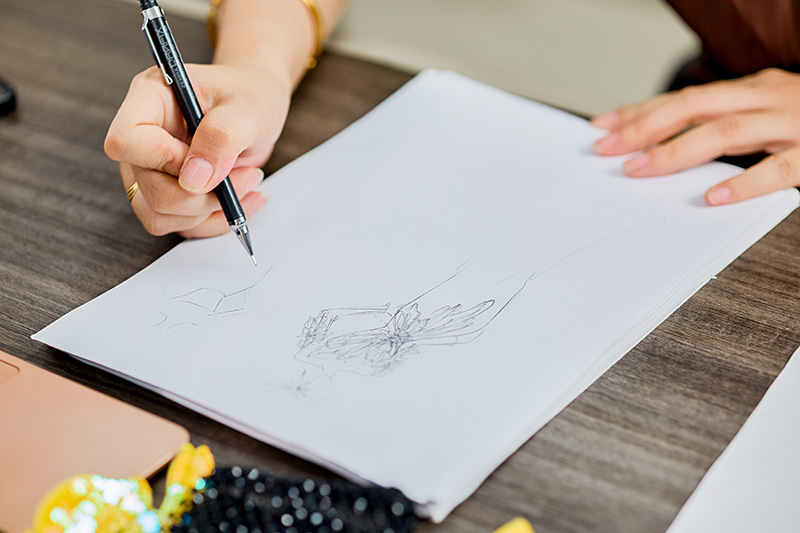 Handtekening van een coutureontwerp op een werktafel, naast kralenmaterialen